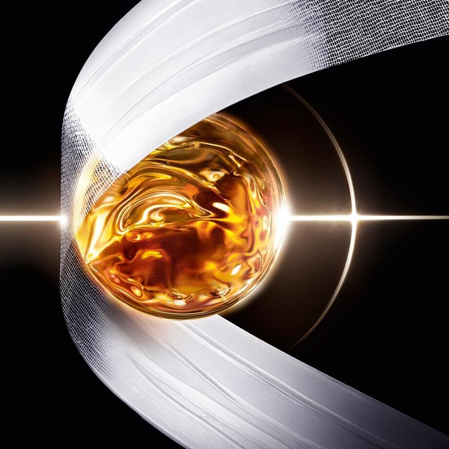 Un globe dore entoure d'un ruban blanc, illumine par une lumiere brillante sur fond noir.