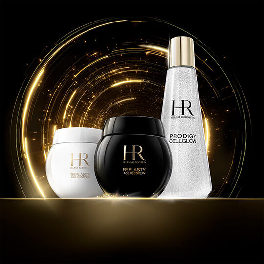 Cremes Helena Rubinstein Re-Plasty Age Recovery (pots noirs et blancs) et une bouteille Prodigy Cellglow, sur fond de lumiere doree etincelante sur noir.