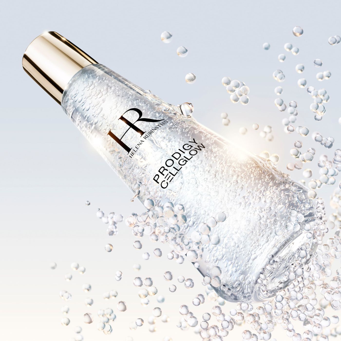 Flacon de serum "Helena Rubinstein Prodigy Cellglow" rempli de bulles, incline et entoure de bulles eclatantes en suspension, sur un fond clair et lumineux.