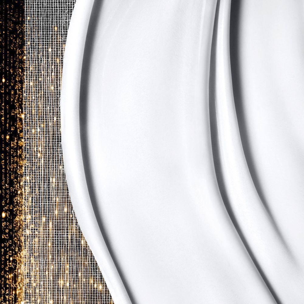 Texture blanche, lisse et cremeuse avec des vagues douces sur le cote droit, juxtaposee a des motifs dores scintillants et abstraits sur le cote gauche.